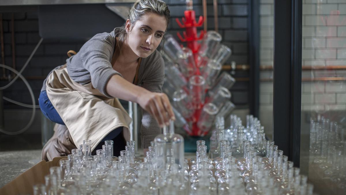 Mujer colocando botellas de cristal