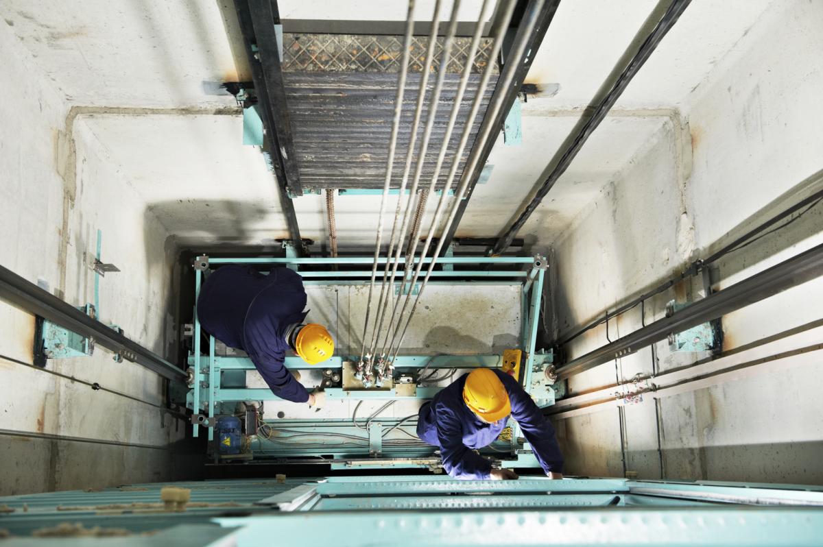 Dos operarios trabajan en el interior de un ascensor